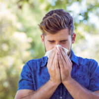 Young man sneezing due to seasonal allergies in Florida