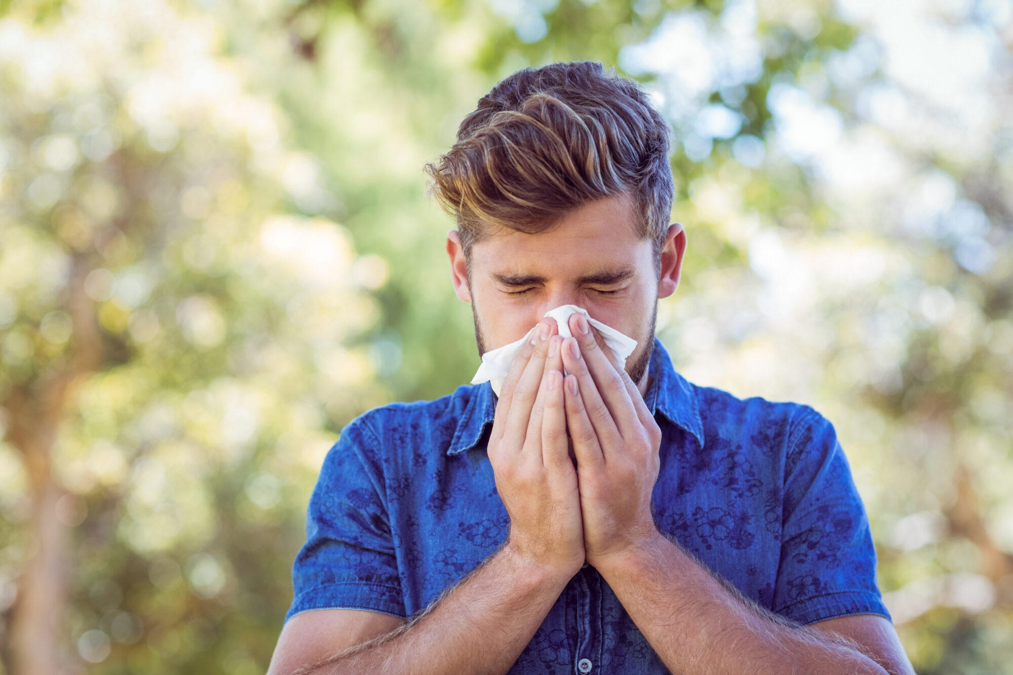 Young man sneezing due to seasonal allergies in Florida