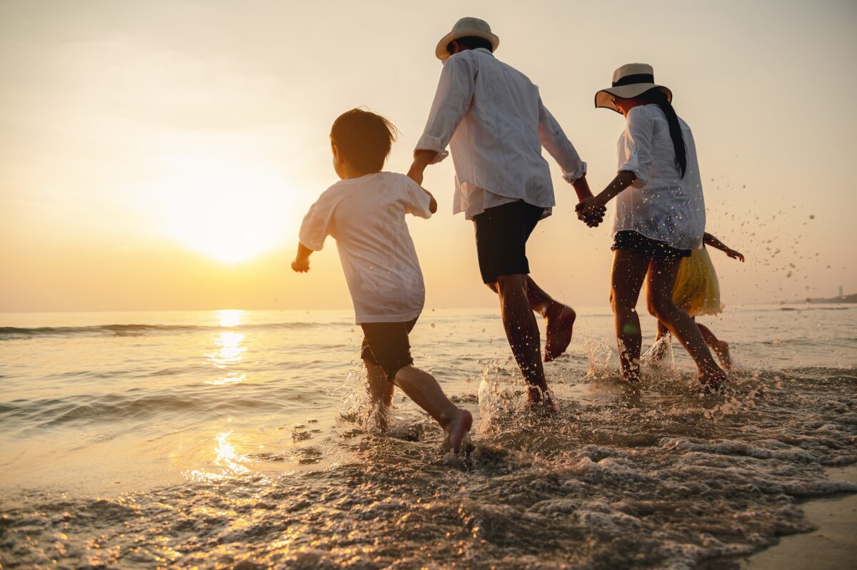 Happy family running through the sand at the beach together.